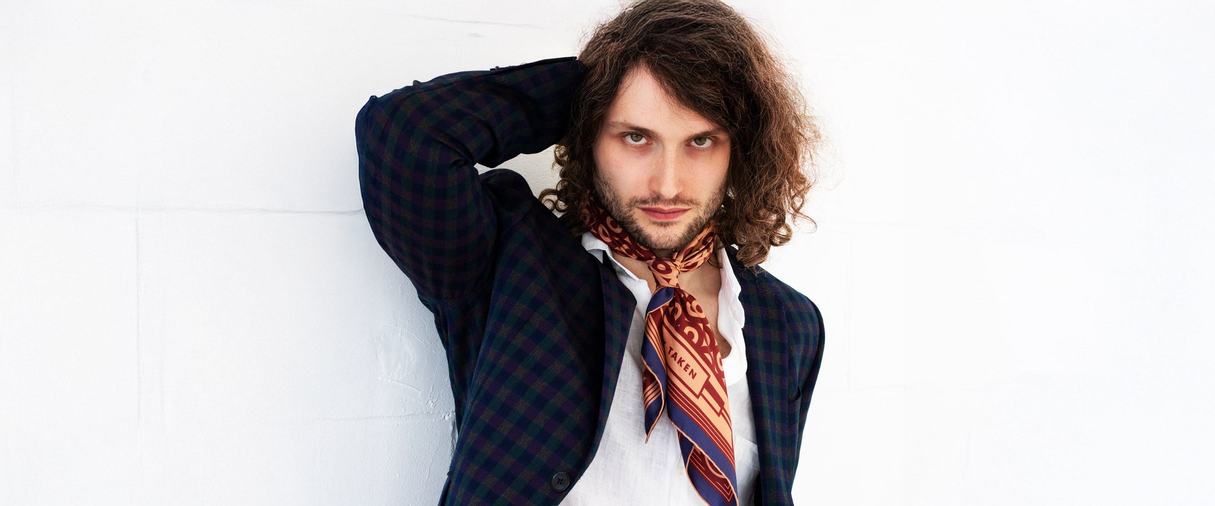 Long haired model wearing a blue suit and a coloured silk neckerchief