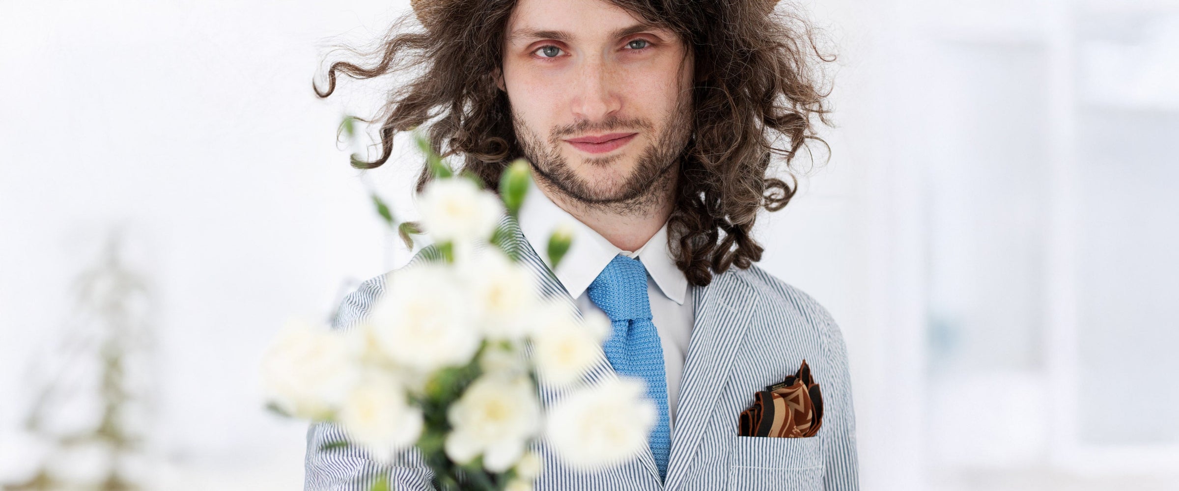 Model with bunch of flowers wearing a woven silk tie in pale blue