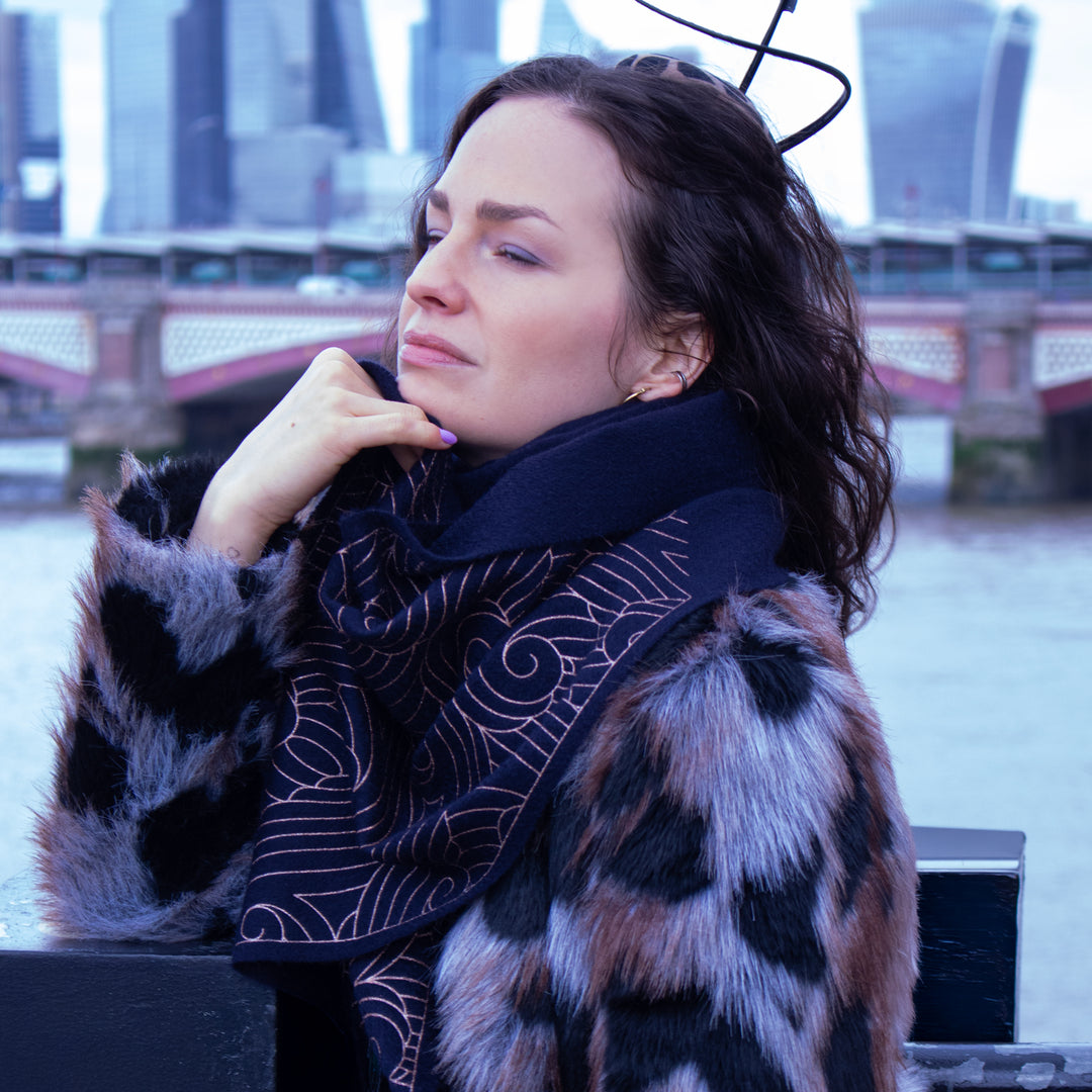 Woman wearing a patterned scarf and fur coat with a cityscape in the background